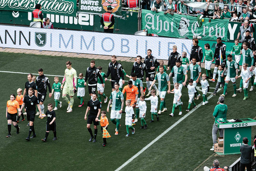 Die Mannschaften vom SV Werder Bremen und Borussia Mönchengladbach laufen ins Weserstadion ein.