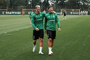 Dawid Kownacki und Marco Friedl gehen in Arm vom Trainingsplatz.