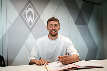 Mitchell Weiser looks into the camera as he signs his new contract.