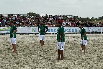 Die Spieler stehen auf dem Sandplatz.