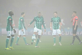 Die Spieler warten im Nebel mit dem Ball. 