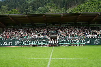 Großes Mannschaftsfoto vor der Huaptribüne mit zahlreichen Werder-Fans