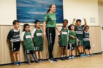 Eine Gruppe von Kindern und eine Trainerin stehen nebeneinander