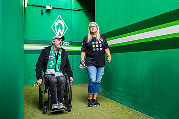 Ein Fan im Rollstuhl geht mit Werders Behindertenbeauftragter, Alexandra Lüddecke, ins Stadion.