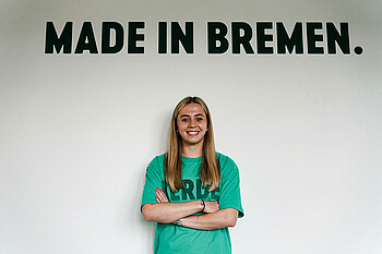 Nina Lührßen steht vor der Wand mit Aufschrift Made in Bremen