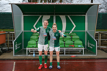 Lina Hausicke und Nina Lührßen stehen vor der Trainerbank.