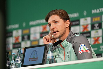 Niklas Stark talks into the microphone in the press conference room. 