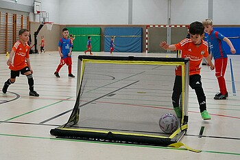 Vier Kinder spielen Fußball auf ein kleines Tor