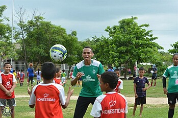 Young Coach mit Werder-Trikot erklärt Kindern eine Übung.