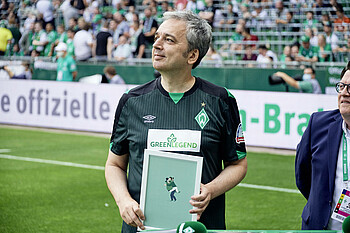 Arnd Zeigler mit einem Gemälde in der Hand im Weserstadion