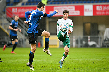 Romano Schmid streckt im Sprung sein Bein, um vor einem Paderborner an den Ball zu kommen.