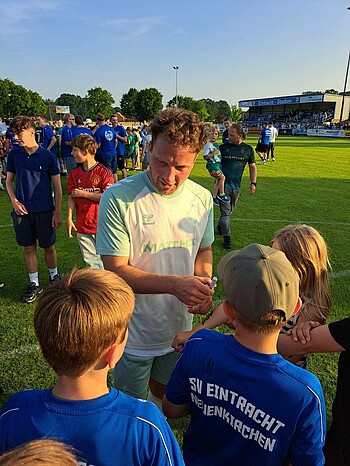 Phillip Bargfrede gibt nach dem Spiel Autogramme auf dem Rasen. 