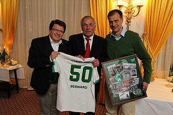 Hess-Grunewald und Filbry überreichen Bernard ein Trikot mit der 50 drauf. 