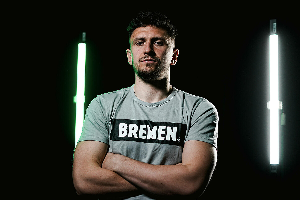 Milos Veljkovic trägt ein Tshirt mit der Aufschrift "Bremen" und verschränkt die Arme.
