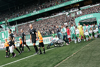 Die Schiedsrichter laufen vorweg, dahinter der Rollstuhlfahrer Niklas und danach die Mannschaften.