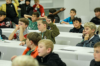 Ein Junge hebt den Finger bei der Kids Pressekonferenz