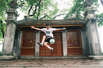 Freestyler "PhatFreestyle" juggling the ball in front of a landmark.