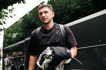 Milos Veljkovic mit Kleidung in der Hand vor dem schwarzen Bus.