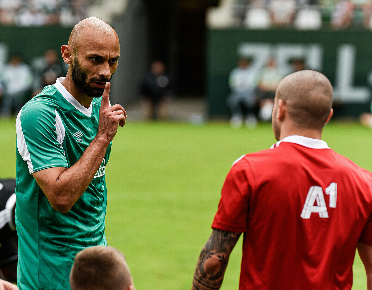 Ömer Toprak mit erhobenem Zeigefinger im Gespräch mit einem Gegenspieler.