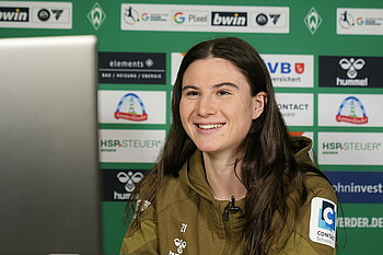 Chiara Hahn in der Mixed Zone lachend vor dem Laptop.