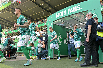 Werder-Spieler laufen in Aufwärmshirts durch den Spielertunnel auf das Spielfeld.