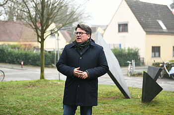 Dr. Hubertus Hess-Grunewald steht vor einer Skulptur und hält eine Rede.