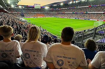 Zwei Teilnehmende des Special Youth Camp sitzen im Stadion.
