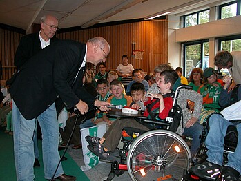 Ehrenpräsident Klaus-Dieter Fischer im Gespräch mit einem Schüler im Rollstuhl.