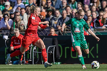 Caroline Siems schießt, eine Bayern-Spielerin läuft auf sie zu.