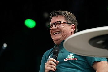 Dr. Hubertus Hess-Grunewald lacht mit dem Mikrofon in der Hand.