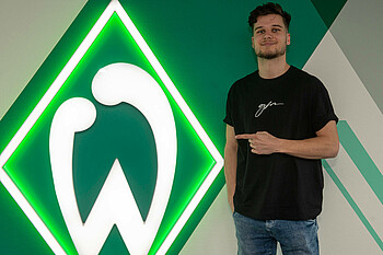 Tim van de Schepop vor der Raute des SV Werder Bremen nach seiner Vertragsunterzeichnung