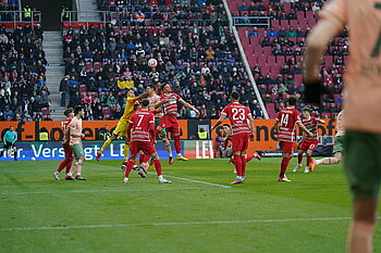 Marco Friedl in an aerial duel with multiple Augsburg players.