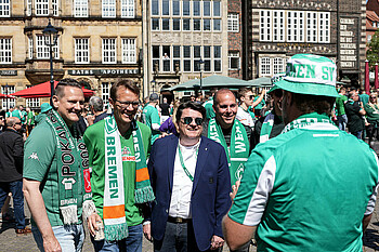 Hubertus Hess-Grunewald posiert mit Fans für ein Foto auf dem Marktplatz.