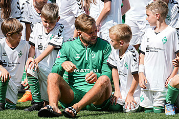 Niclas Füllkrug inmitten Kindern der Fußballschule.