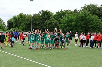 Die Mannschaft reißt die Arme hoch und jueblt gemeinsam mit dem Pokal.