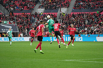 Niclas Füllkrug wins a header against two Leverkusen players.
