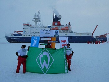 Die Besatzung mit einer Werder-Fahne vor der Polarstern.