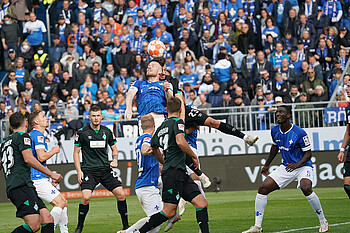 Mehrere Bremer im Pulk um Nicolai Rapp der im Kopfballduell mit einem Darmstädter hochspringt.