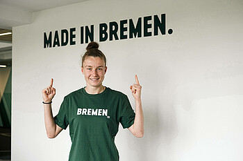 Michelle Ulbrich zeigt auf den Schriftzug Made in Bremen