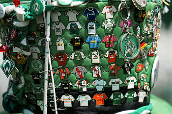 Auf dem Hut sind dutzende Pins von Werder-Trikots angebracht.