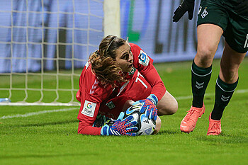 Catalina Perez liegt auf der Seite und hat den Ball in den Handschuhen.