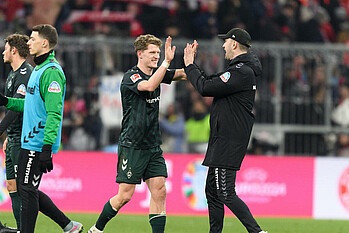 Jens Stage klatscht mit Ole Werner nach dem Sieg in München 2024 ein.