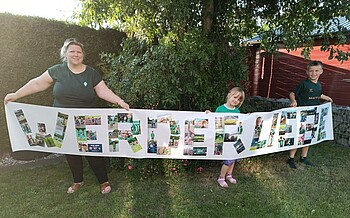 Die Familie präsentiert die große Collage im eigenen Garten. 