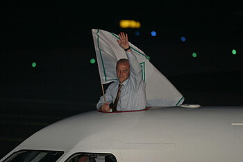 Thomas Schaaf hält eine Werder-Fahne aus der Luke des Flugzeugs. 