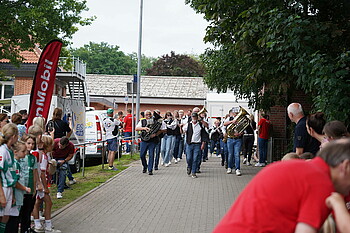 Eine Blaskapelle marschiert auf den Sportplatz ein.