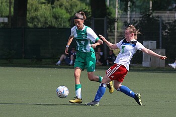 Eine Spielerin von Werder führt den Ball am Fuß, eine HSV-Spielerin setzt zur Grätsche an.