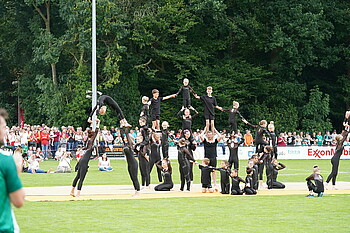 Eine Akrobatik Gruppe präsentiert eine Choreografie auf dem Rasen