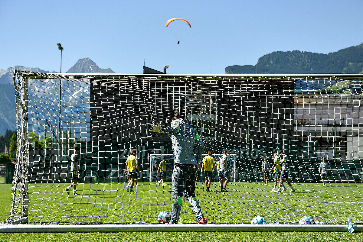 Werders Mannschaft auf dem Trainingsplatz im Zillertal, über dem Feld schwebt ein Paraglider.