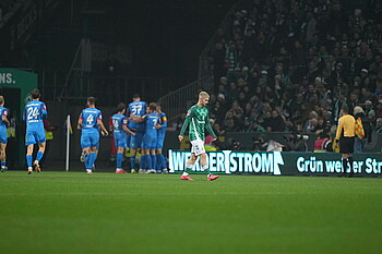 Romano Schmid and Werder players show disappointment after conceding, with Kiel players celebrating in the background