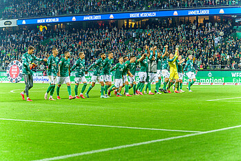 Die Werder Spieler machen vor der Ostkurve eine Laola-Welle.